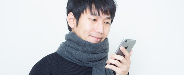 スマホを見ているマフラーを巻いた男性